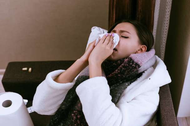 sad young girl is very sick because of the cold winter weather, sneezes, headache - Foto, Imagen