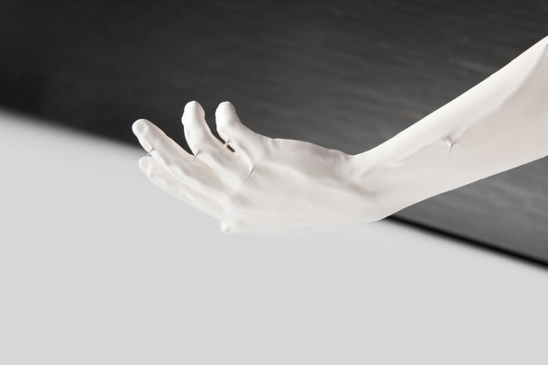 cropped image of female hand in white paint above black and white surface - Foto, afbeelding