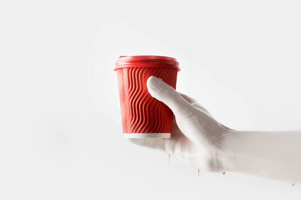 abgeschnittenes Bild einer Frau in weißer Farbe mit roter Einweg-Kaffeetasse isoliert auf weißer Farbe - Foto, Bild