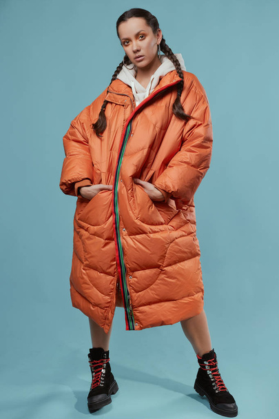 Портрет очаровательной латиноамериканской девушки в длинном оранжевом пальто
 - Фото, изображение