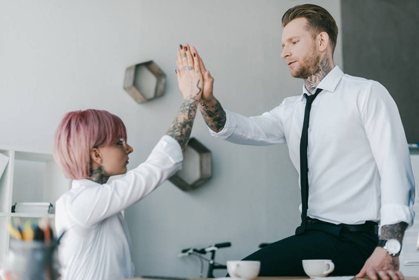 young tattooed business colleagues giving high five in office - Foto, afbeelding