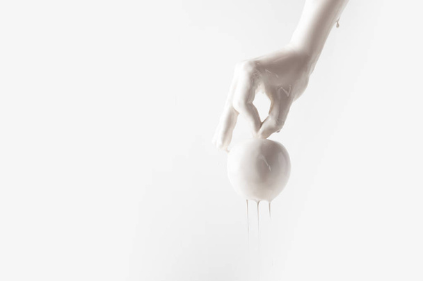 cropped image of woman in white paint holding apple isolated on white - Фото, изображение