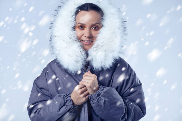 Красива чарівна іспаномовна дівчина в синьому пальто з падаючим снігом
 - Фото, зображення