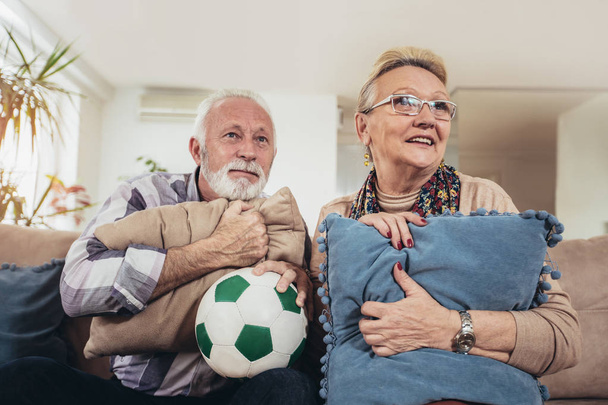Feliz casal sênior assistindo futebol na TV e celebrando a vitória em casa
 - Foto, Imagem