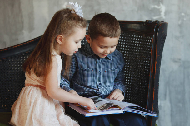 Niño y niña leyendo interesante libro
 - Foto, imagen