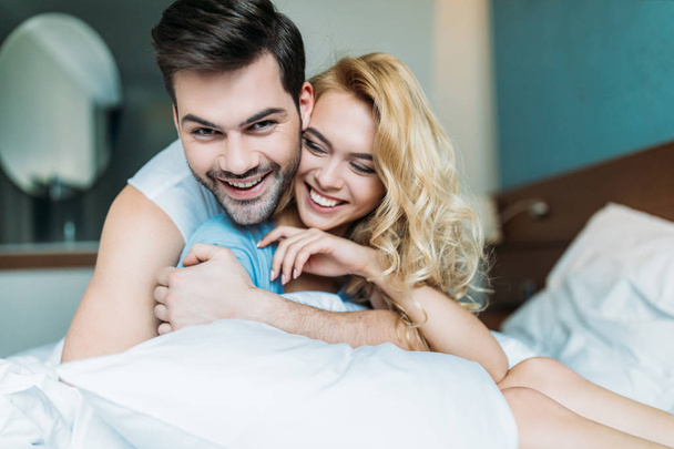 smiling heterosexual couple hugging on bed  - 写真・画像