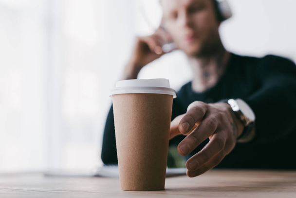 close-up view of young businessman reaching for paper cup on table - Foto, immagini