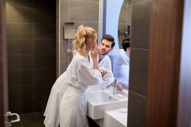 boyfriend looking how girlfriend applying cream on face  - Photo, Image