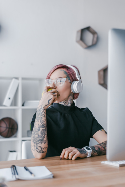 jovem empresária em fones de ouvido e óculos olhando para o local de trabalho
  - Foto, Imagem