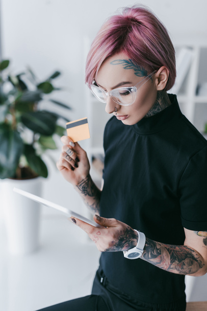 young tattooed businesswoman holding credit card and using - Valokuva, kuva