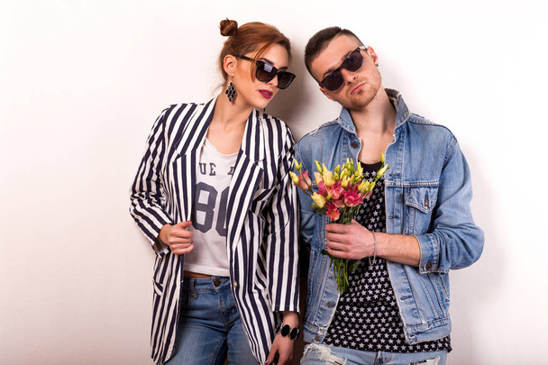 hipster couple in love with a bouquet of flowers in the studio at Christmas, the concept of Valentine's Day - Photo, image