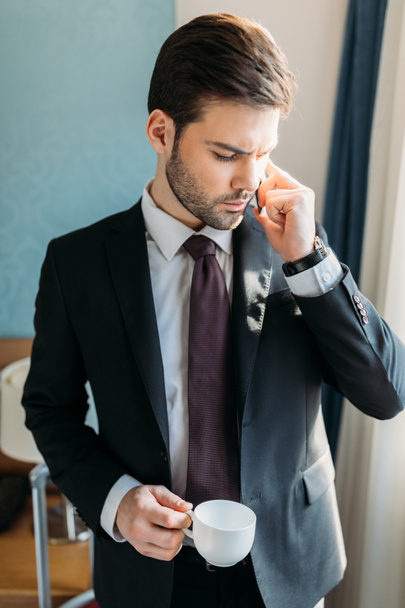 красивий бізнесмен розмовляє по смартфону в готельному номері
 - Фото, зображення