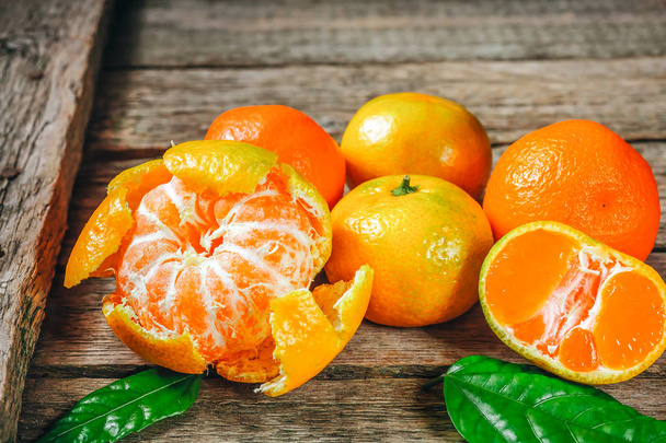 Dużo świeżych Mandarynkowa pomarańcza lub mandarine z zielony liści na drewnianej podłodze - Zdjęcie, obraz