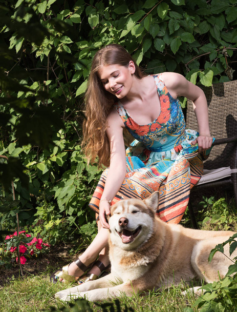 Uma jovem a acariciar um cão. Retrato de verão ao ar livre
 - Foto, Imagem