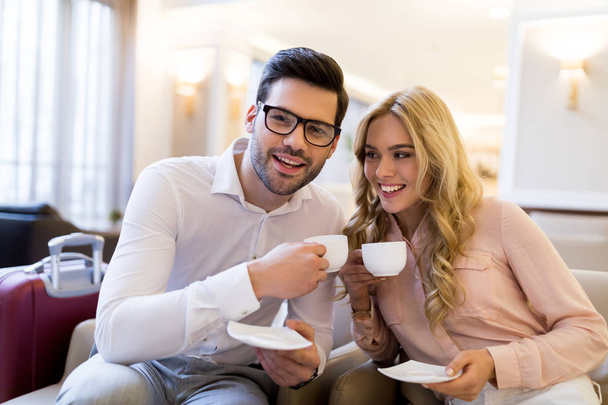 smiling couple of travelers holding cups of coffee - Photo, Image