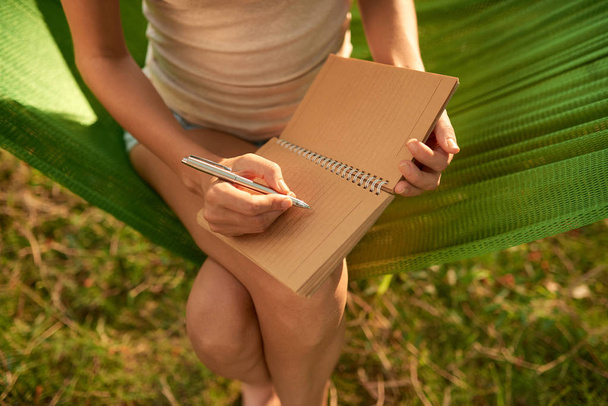 Visão de alto ângulo da mulher tomando notas necessárias no diário
 - Foto, Imagem