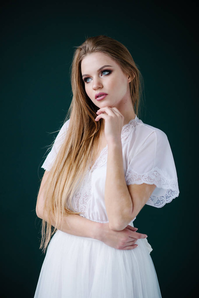 Beautiful young woman with make up  in white dress posing in studio - 写真・画像