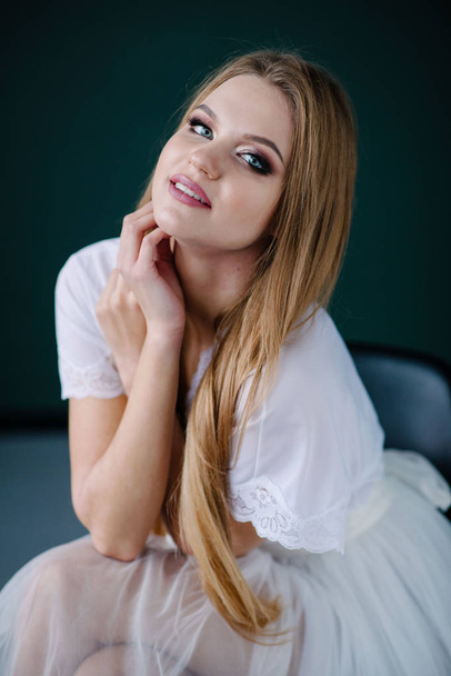 Beautiful young woman with make up  in white dress posing in studio - Fotó, kép