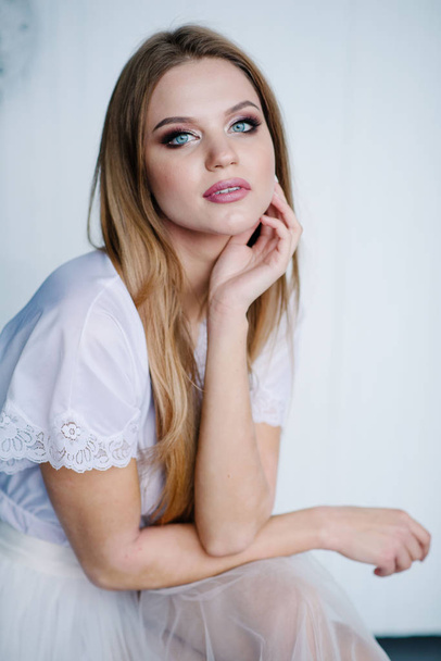 Beautiful young woman with make up  in white dress posing in studio - Valokuva, kuva