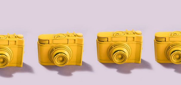 パステルの行に立っているヴィンテージの黄色のカメラはピンク色です。写真コンセプト. - 写真・画像