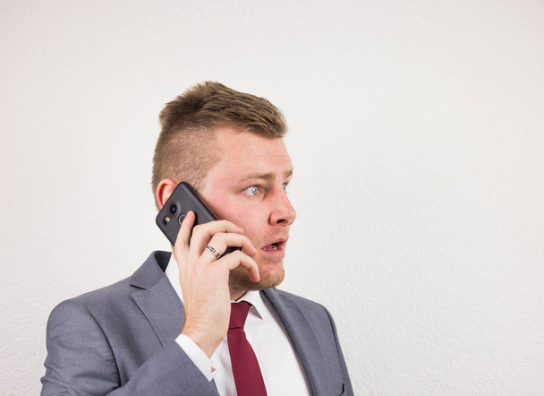 ein junger Geschäftsmann im Anzug, der auf einem Handy spricht, macht sich Sorgen - Foto, Bild