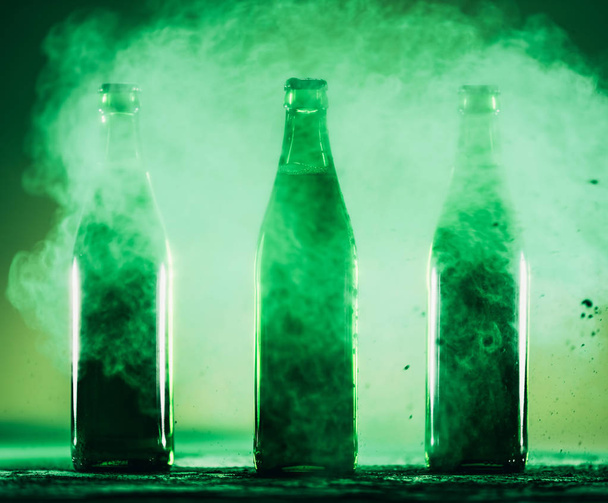 緑のほこりに立っている 3 つの緑の瓶。聖パトリックの日。アイルランド飲料. - 写真・画像