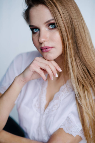 Beautiful young woman with make up  in white dress posing in studio - Фото, зображення
