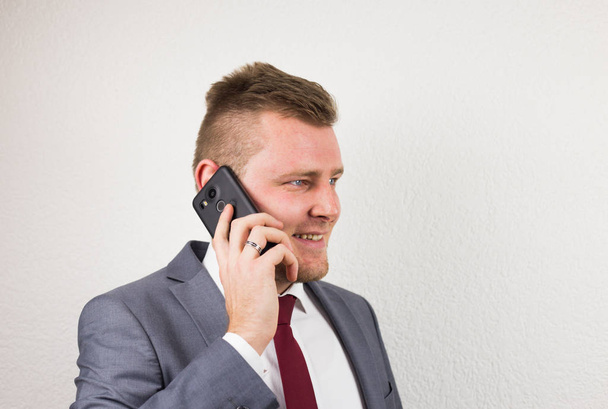 Молодой бизнесмен в костюме, разговаривает по мобильному телефону, устраивает
 - Фото, изображение