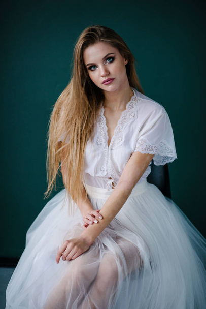 Beautiful young woman with make up  in white dress posing in studio - Photo, image