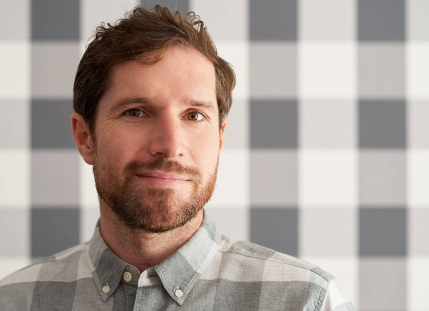 Close up of happy young man with beard standing in front of wallpaper wearing matching shirt - Photo, Image