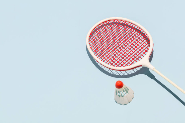 Oldschool badminton racket and birdie laying on a pastel blue background. Sports and leisure activities. - Foto, Imagem