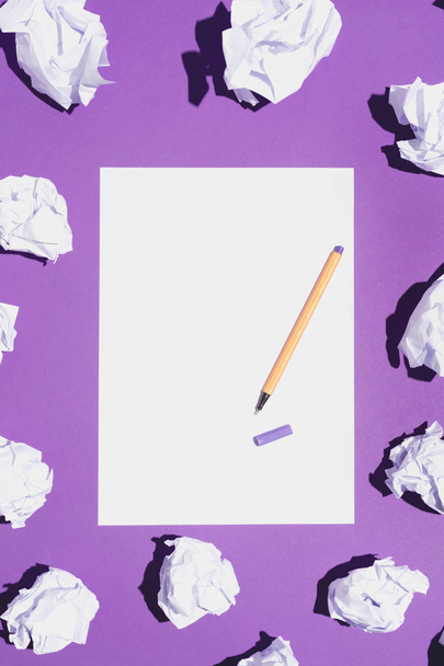 Blank white page and fineliner laying on vivid violet background, creased paper around it. - Photo, image