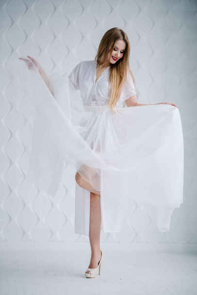 Όμορφη νεαρή γυναίκα με μακιγιάζ σε λευκό φόρεμα που θέτουν σε στούντιο - Φωτογραφία, εικόνα