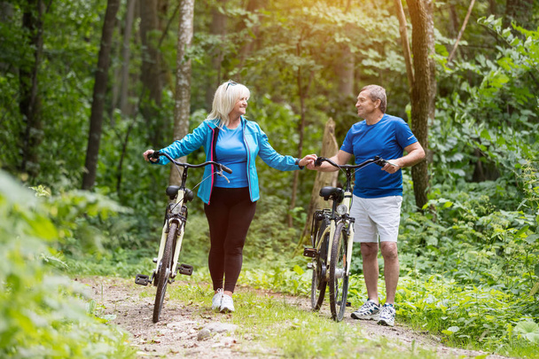 Ältere Ehen mit Fahrrädern, die Händchen halten. Aktivitäten im Freien. Erhalt der Gesundheit. - Foto, Bild