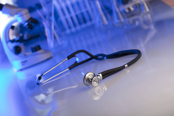 Gezondheidszorg, medische concept. Stethoscoop, Microscoop, achtergrond van het laboratorium, lab glaswerk. Blauwe achtergrond.  - Foto, afbeelding