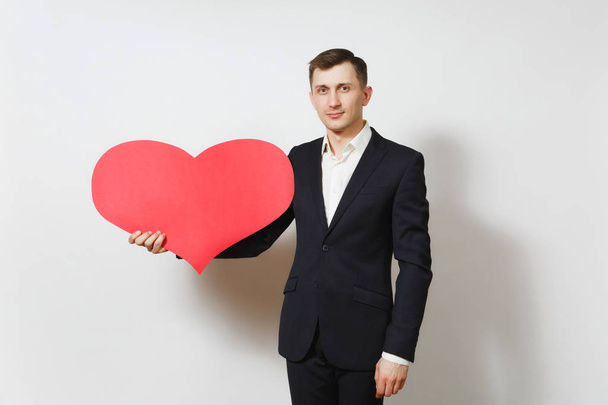 Young handsome man in suit holding big red heart isolated on white background. Copy space, advertisement. Place for text. St. Valentine's Day, International Women's Day, birthday, holiday concept. - Fotografie, Obrázek