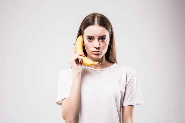 Mulher chamando com uma banana em um fundo branco
 - Foto, Imagem