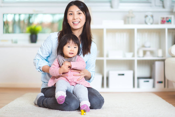 Portrait of a pretty japanese mother holding her cute baby daugh - Foto, Bild