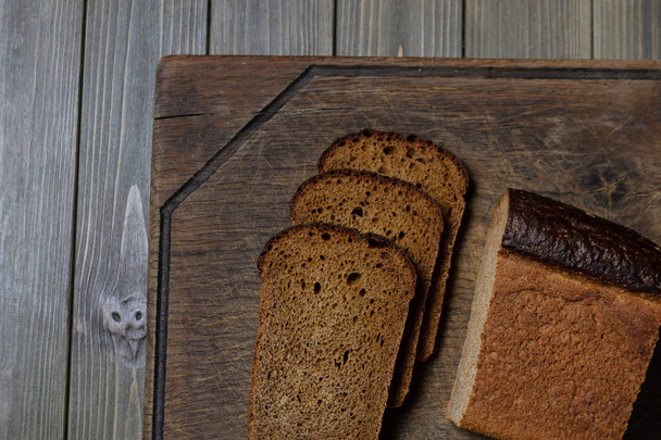 свіжий хліб нарізаний лежить на темній дерев'яній дошці
 - Фото, зображення