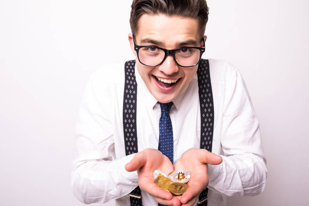 Junger Mann hält goldenen Bitcoin und silbernen Bitcoin in zwei Händen. Nahaufnahme von Bitcoin in offener Hand isoliert auf weißem Hintergrund. - Foto, Bild