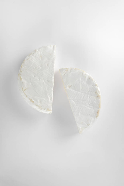 close-up of two pieces of cutting camembert cheese isolated on white background  - 写真・画像