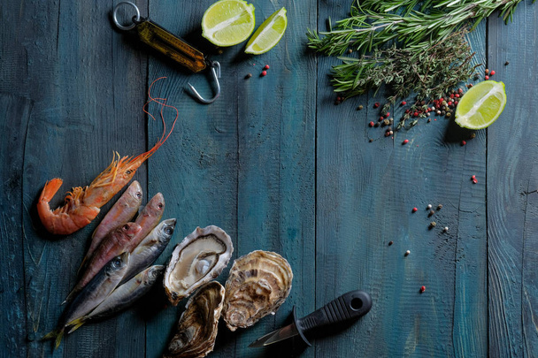 close-up de frutos do mar conjunto de peixes frescos, ostras e camarão com limão sobre fundo mesa de madeira azul
  - Foto, Imagem