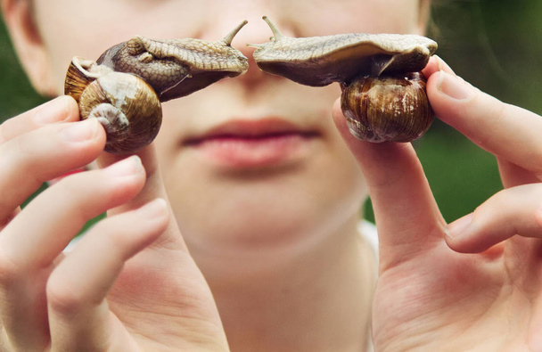 Młoda dziewczyna posiada dwa ślimaki, które z kolei do jeden do jednego. - Zdjęcie, obraz
