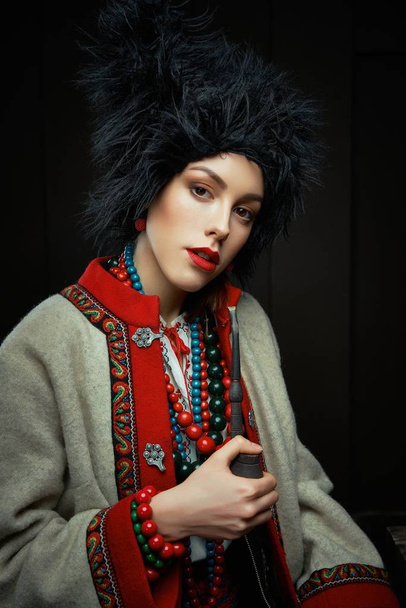 Gorgeous young woman in ukrainian traditional costume smoking pipe  - Photo, image