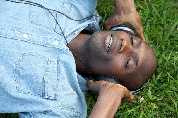 Man laying down in garden with headphones on - Foto, immagini