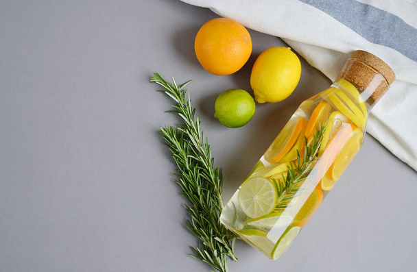 新鮮な水ローズマリー レモン ライム オレンジ色の果実灰色の背景飲料ヘルシー食事とボトル - 写真・画像