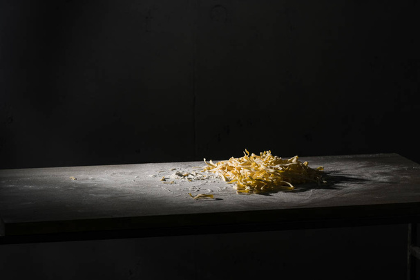 Raw pasta with flour on wooden table. - Foto, Bild