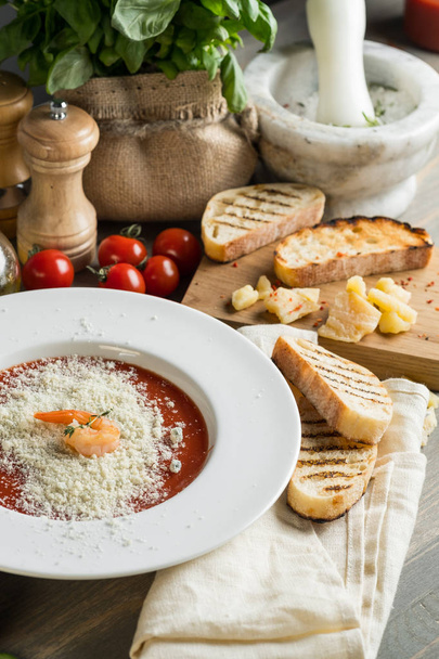 Italian cream soup with cheese, tomato and croutons bread and basil on a wooden grey kitchen table - Foto, Imagen