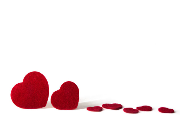 Στέκεται και διάσπαρτα κόκκινο τσόχινοι καρδιές που απομονώνονται σε λευκό φόντο - του Αγίου Βαλεντίνου, αγάπη - Φωτογραφία, εικόνα