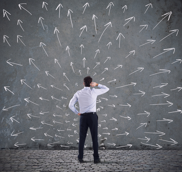 Homme d'affaires confus regardant un mur avec des flèches directionnelles. concept de confusion
 - Photo, image